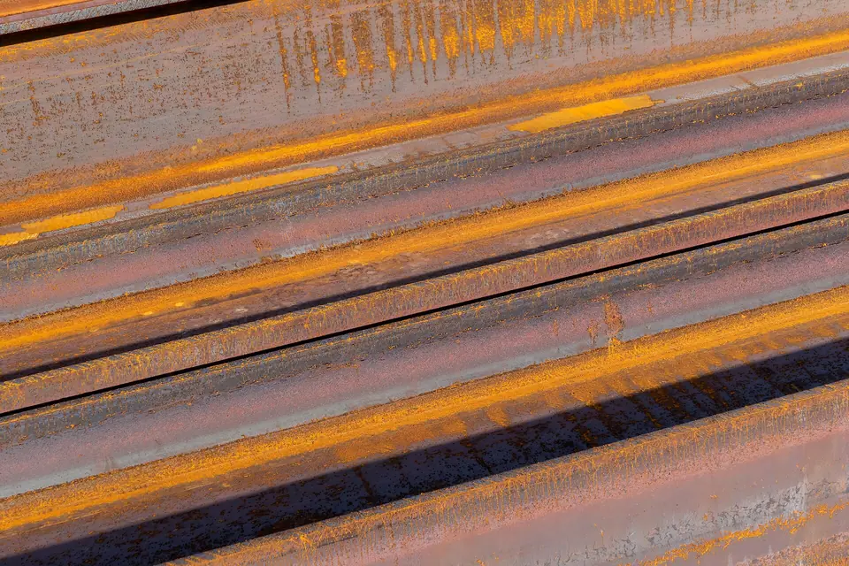 Poutres métalliques en acier à profil en I livrées sur un site de soudure, aux surfaces brutes marquées par la rouille.
