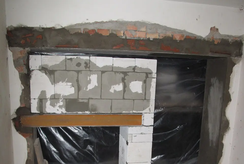 Ouverture dans un mur en briques reprise par deux linteaux superposés, dont un profilé en acier, avec remplissage en blocs de béton cellulaire.